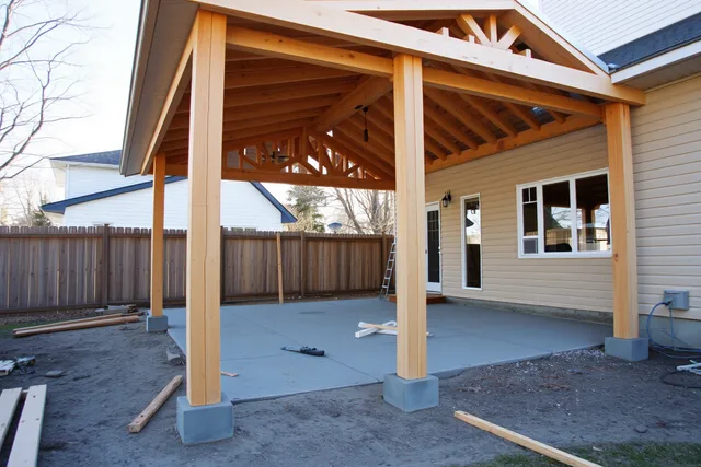 Covered patio under construction with posts, footings and roof framing in Ontario. 3 cost questions for a covered patio in Ontario, from permits to labour