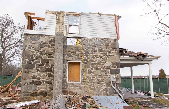 Hired contractors finish the selective demolition process on the modern additions of the house. This is a side view of the house. The repaired historic window is in the center of the original masonry structure. The second floor modern white siding remains only on this side of the house. The front po. Porch restoration contractor or board-replacer: who really restores?
